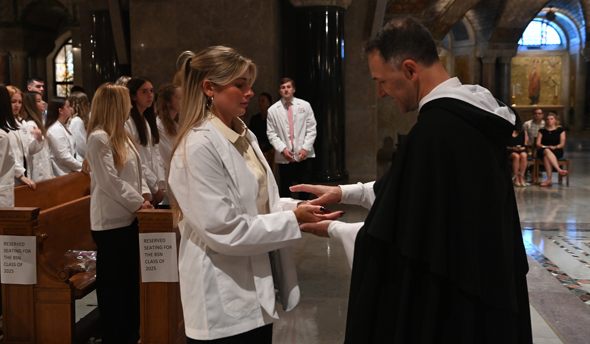 在仪式上，护理系学生的双手受到牧师的祝福. 阿奎那