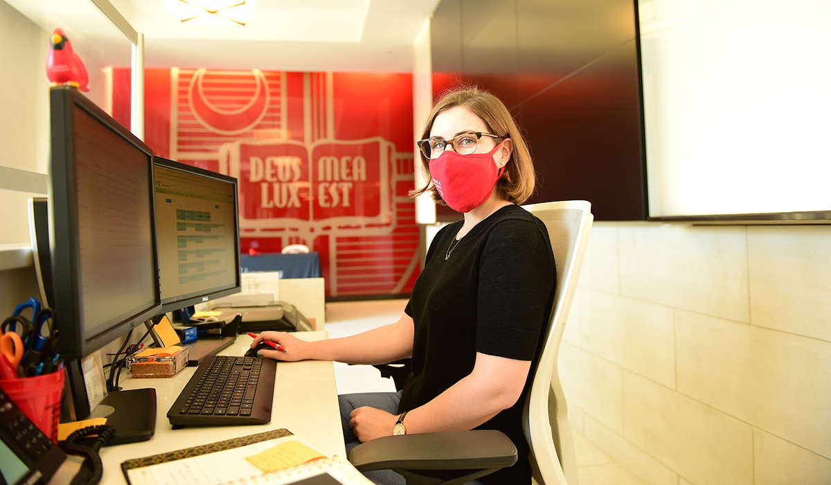 Female employee working at computer while wearing a mask