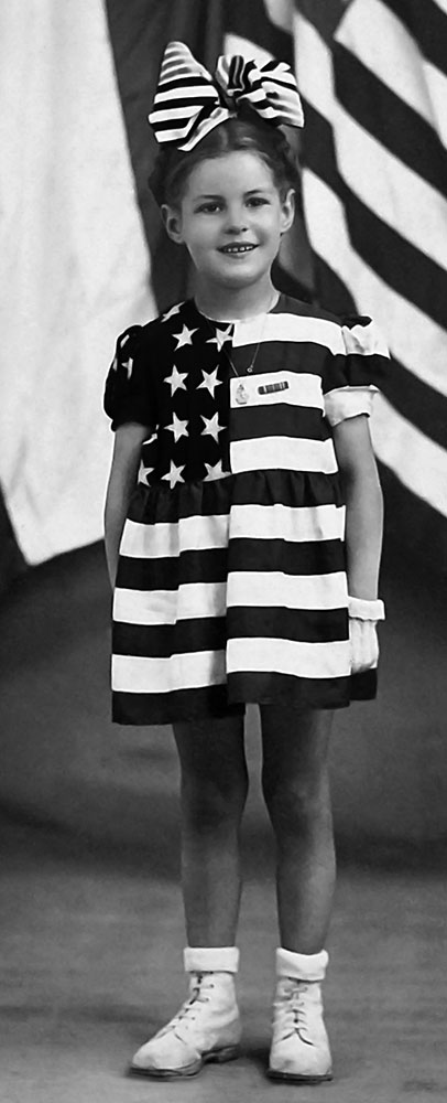 A black and white image of a little girl in an American flag dress