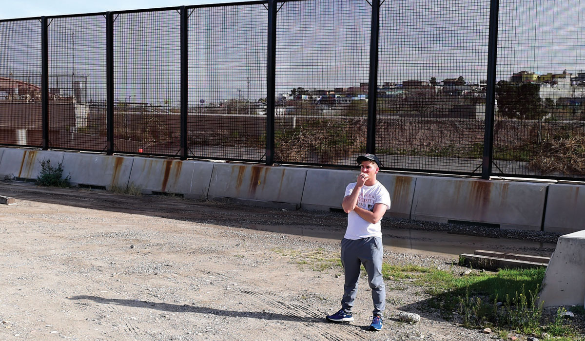 Student standing near the border fence.