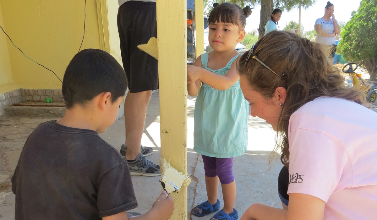 Senior Sarah Turgeon paints alongside local children during a visit to an impoverished colonia in New Mexico.