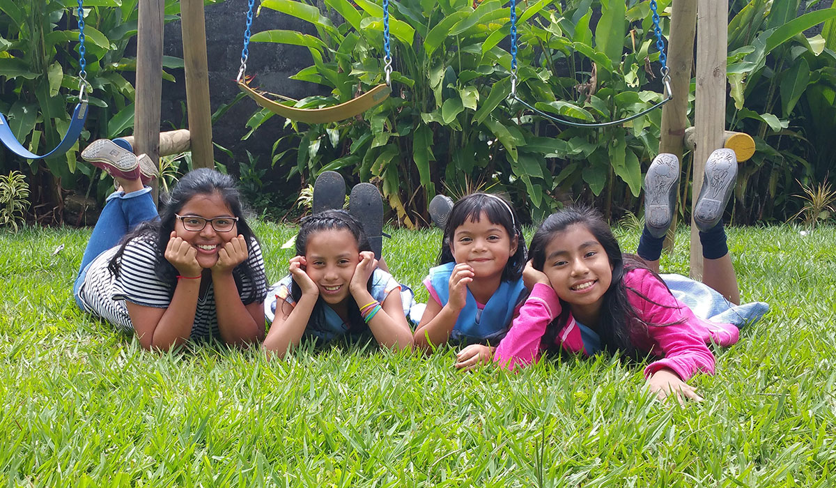 Female graduate sitting on a lawn with children
