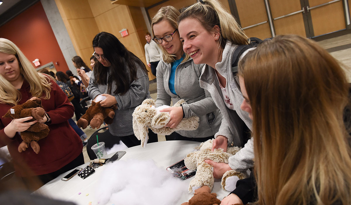 Students laughing while stuffing stuffed animals at Build a Bae