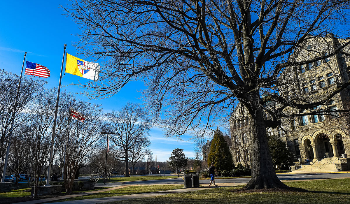 Student walking across campus under blue sky