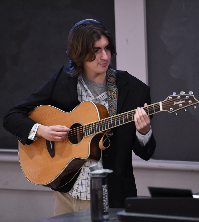Student playing guitar for a physics class