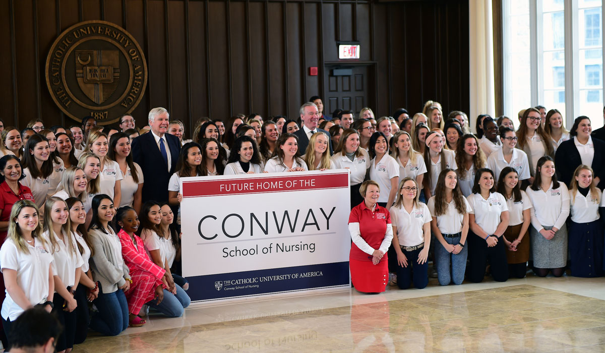 Group photo of leaders and students posing with Conway sign