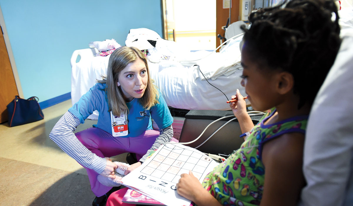 Graceann Kraemer works with a young female patient in a hospital