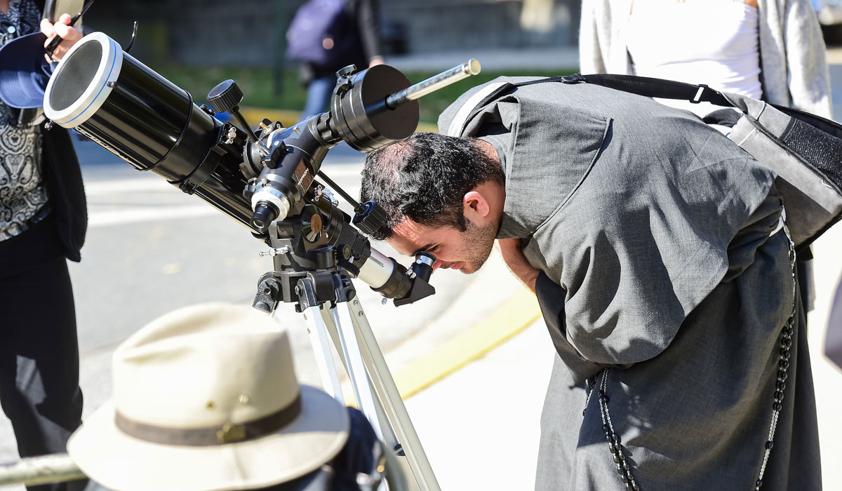 Priest looking through telescope