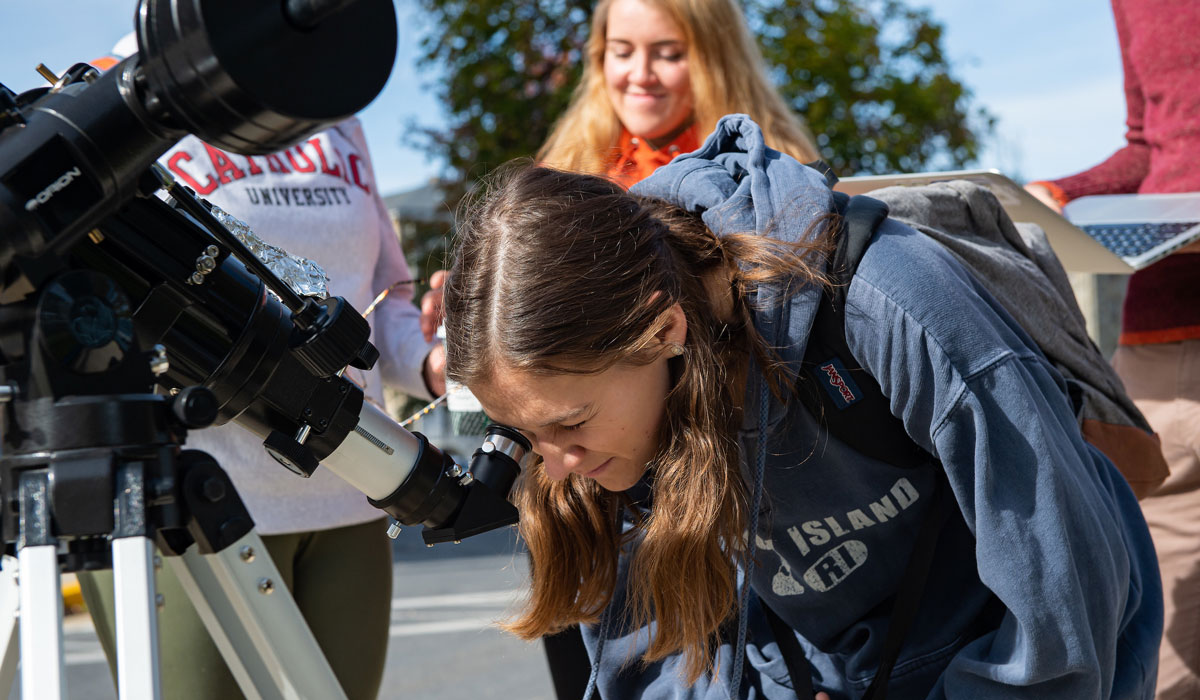 Female student looking through telescope