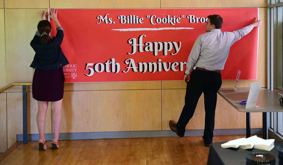 Dining Services employees hang banner for celebration