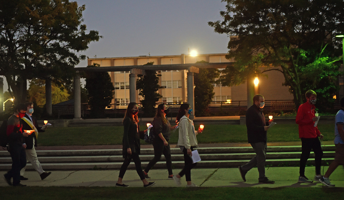 Students walking across campus with candles