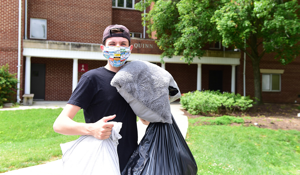 Male student wearing mask while moving out belongings