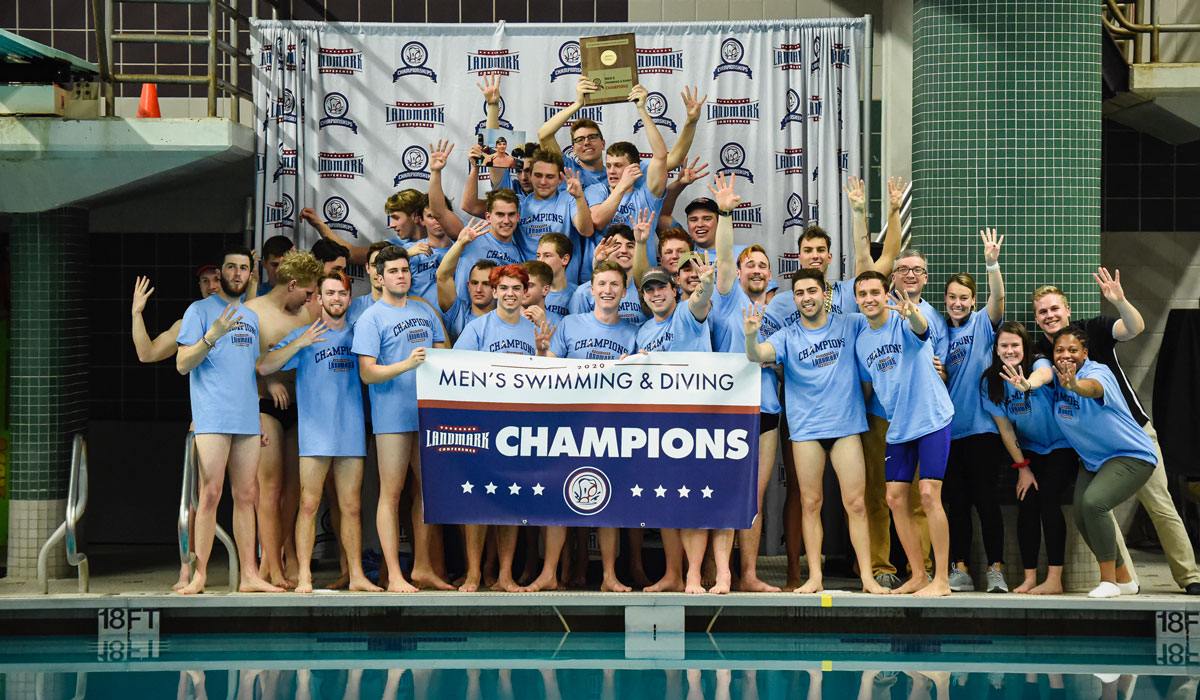 Men's swimming and diving team posing with championship banner