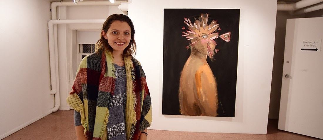A student standing with her painting