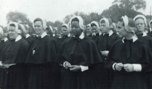 A Black nun standing in the middle of a group of white nuns