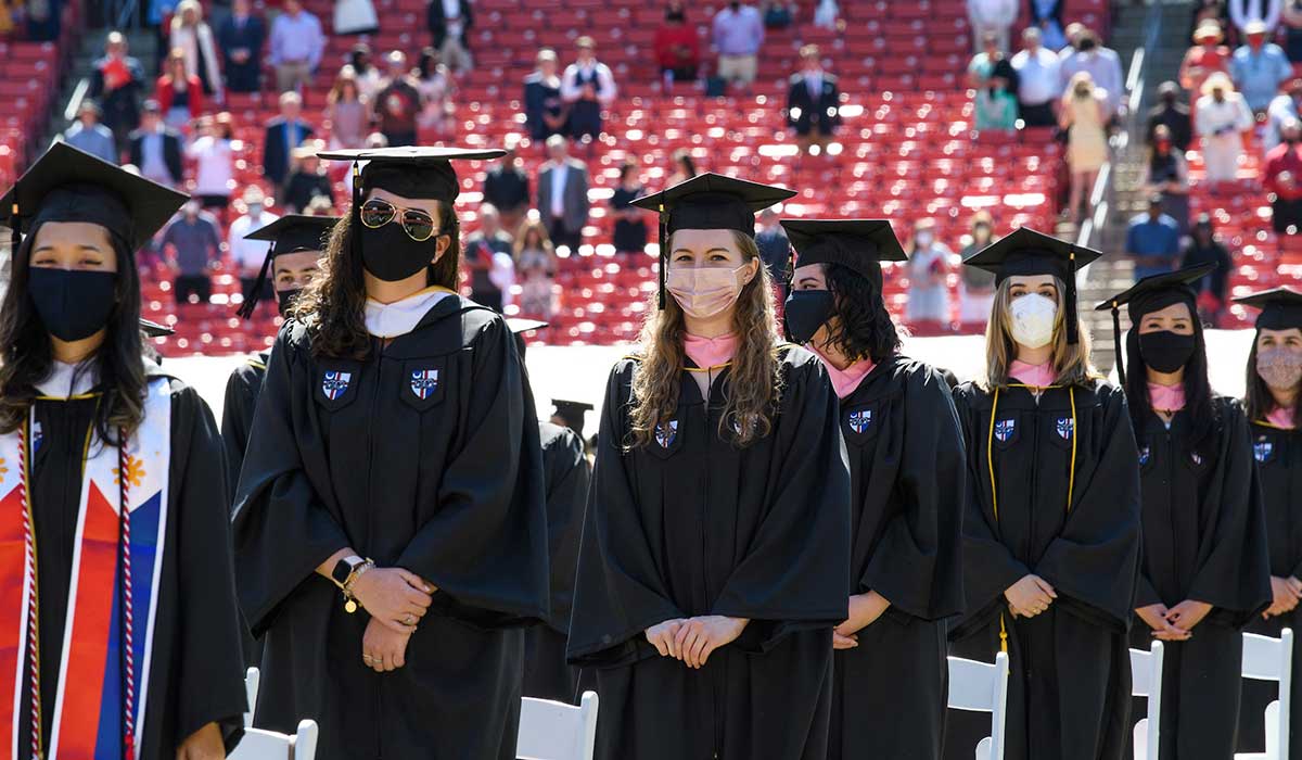 students standing with masks at commencement