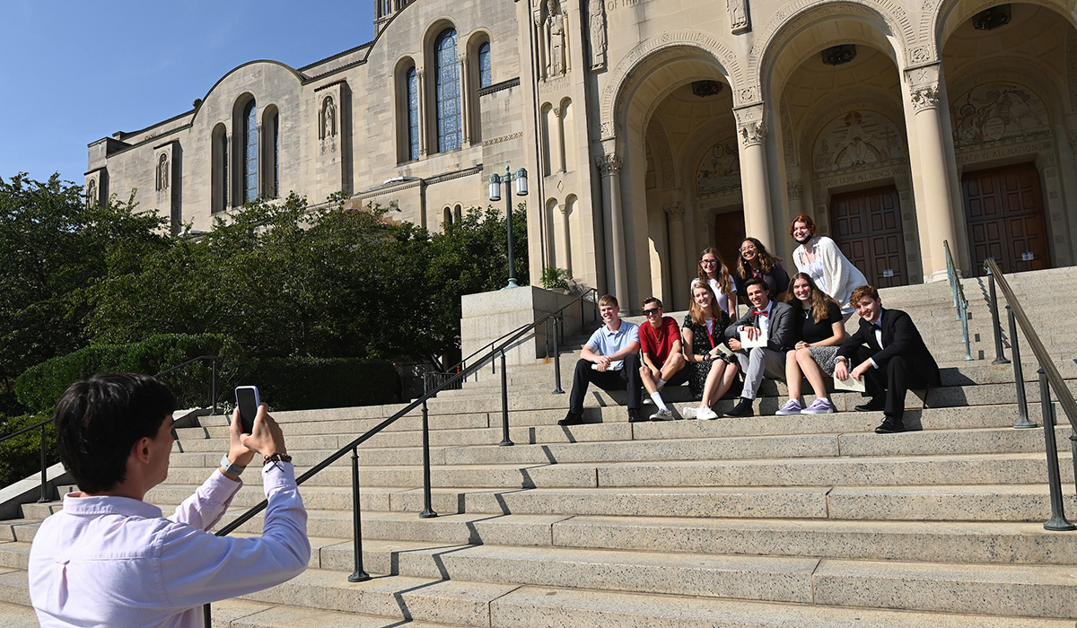 Student taking picture of friends sitting on steps of Basilica