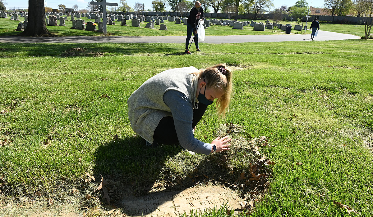 Student cleaning off a grave