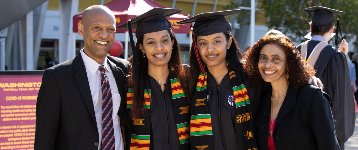 Parents pose with their twin daughters, both in cap and gown