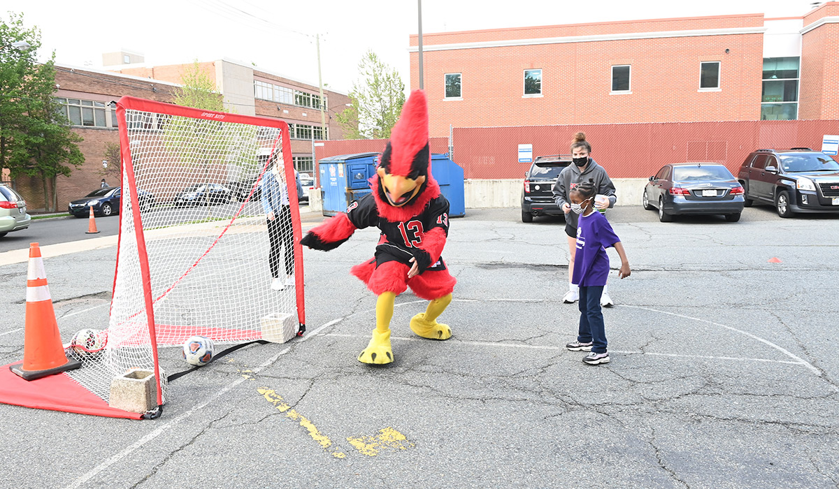 Child scoring a soccer goal against Red the mascot