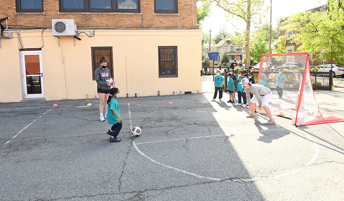 Child kicking soccer ball into a net