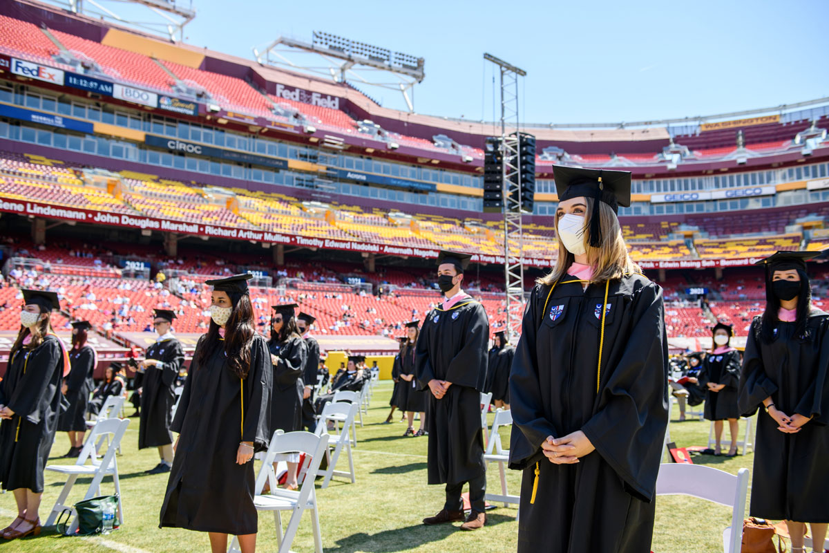 graduates standing at their chairs in FedExField