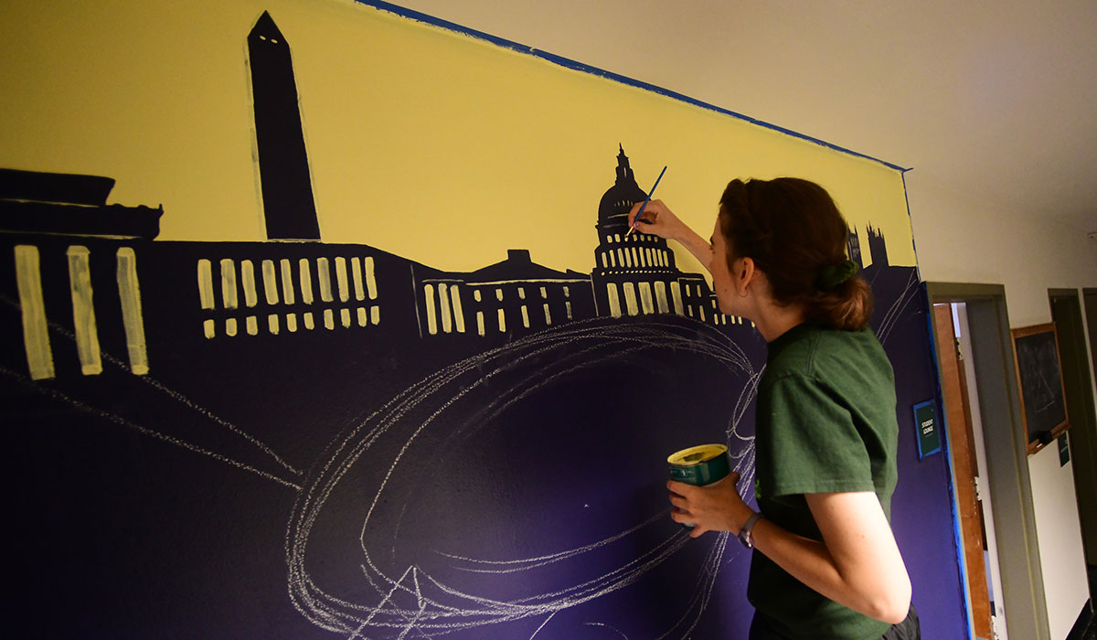 Joanie McMahon using chalk on outline part of mural