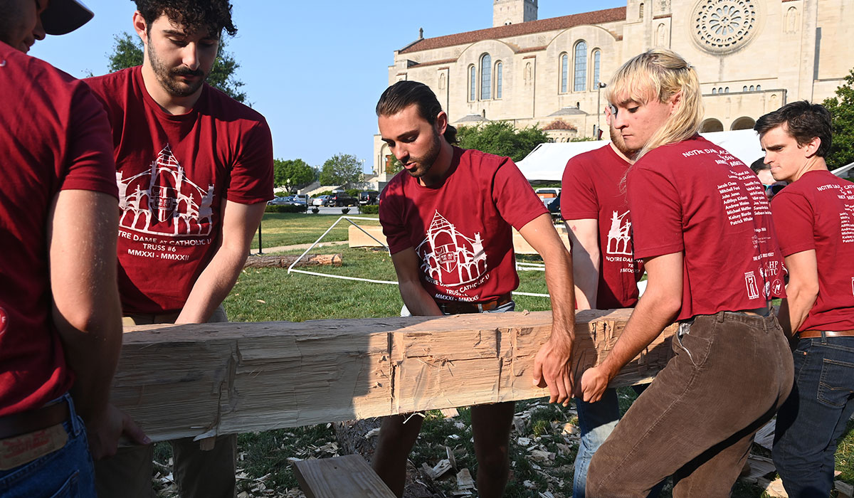 Team of students carrying a wood beam