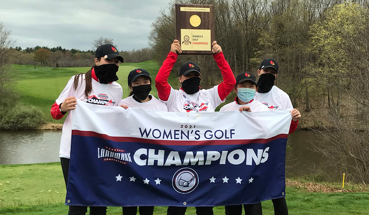 Women's golf team holding up championship banner and trophy