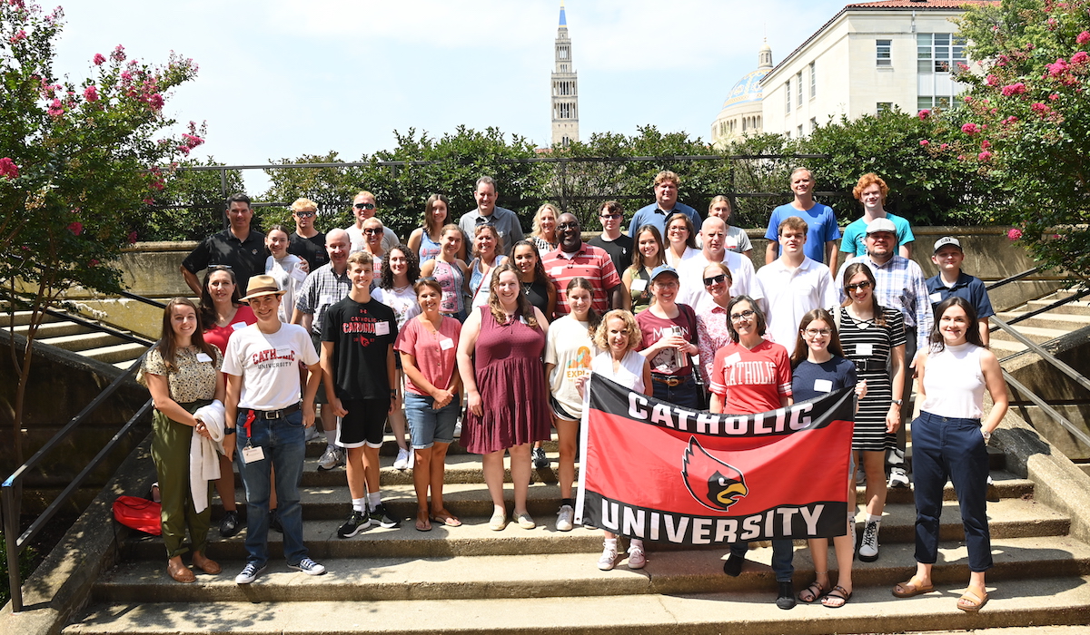 Alumni parents and first-year students pose for a picture with a Catholic University flag
