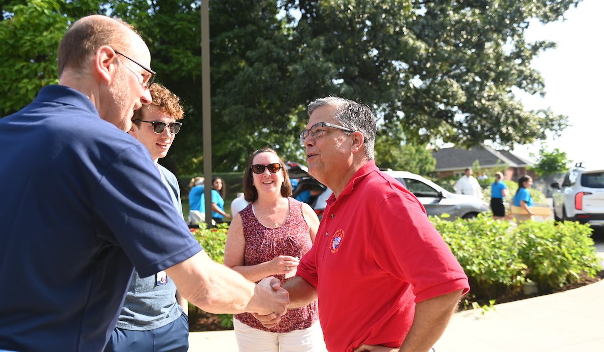 President Kilpatrick shaking a student's dad's hand as he greets him, the student, and the student's mother