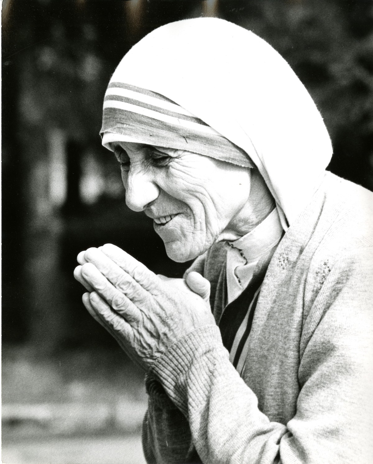 Mother Teresa smiling with hands folded in prayer