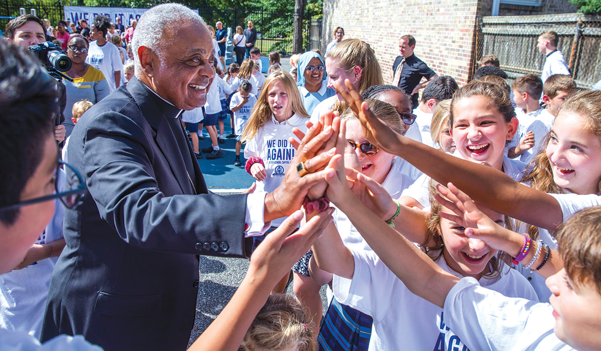 Wilton Gregory shaking hands with students