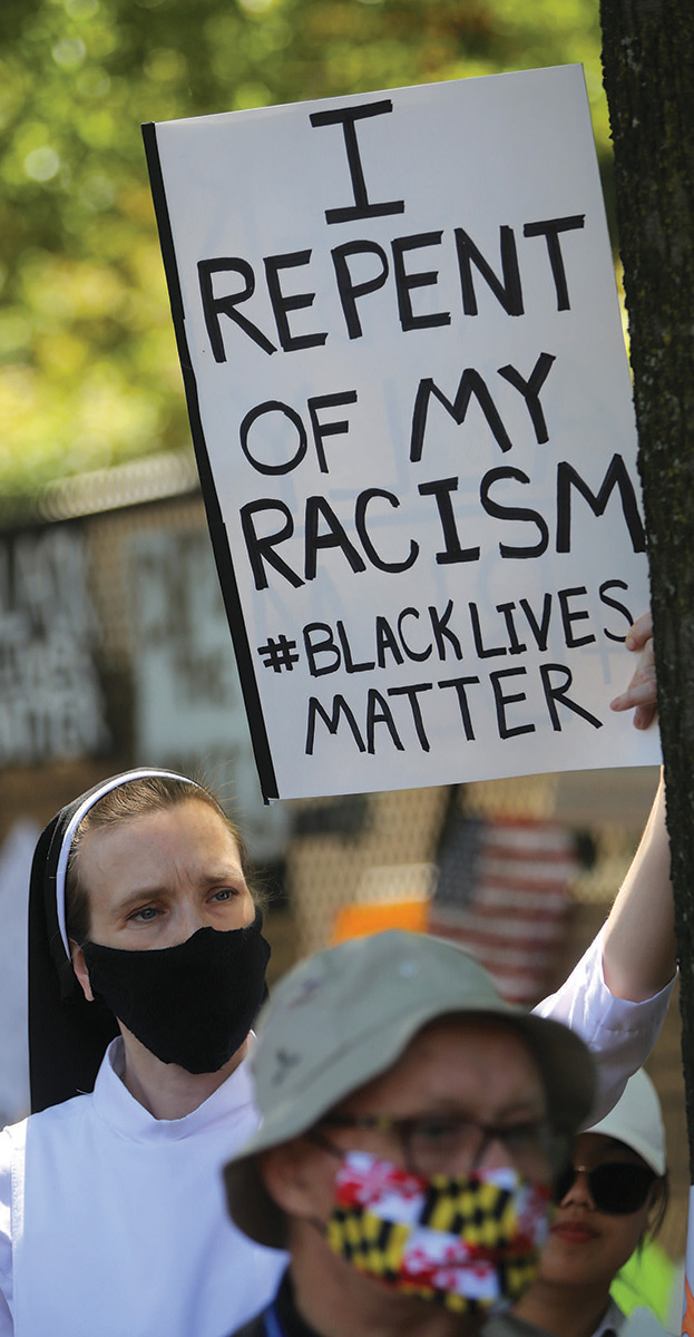 A nun holding up a sign that reads I repent of my racism