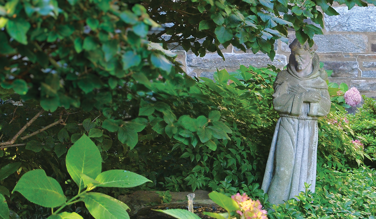 statue of St. Francis amid a small garden on campus