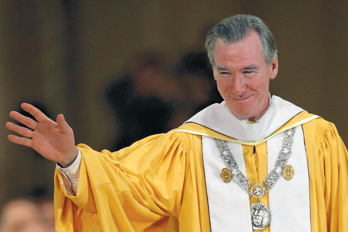 John Garvey waves to someone dressed in his commencement attire