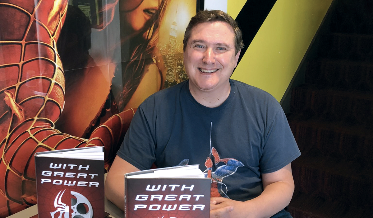 Sean O'Connell smiles with copies of his latest book called With Great Power