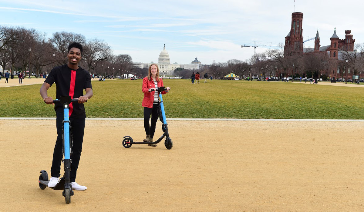 Students riding scooters on the National Mall in front of the U.S. Capitol building