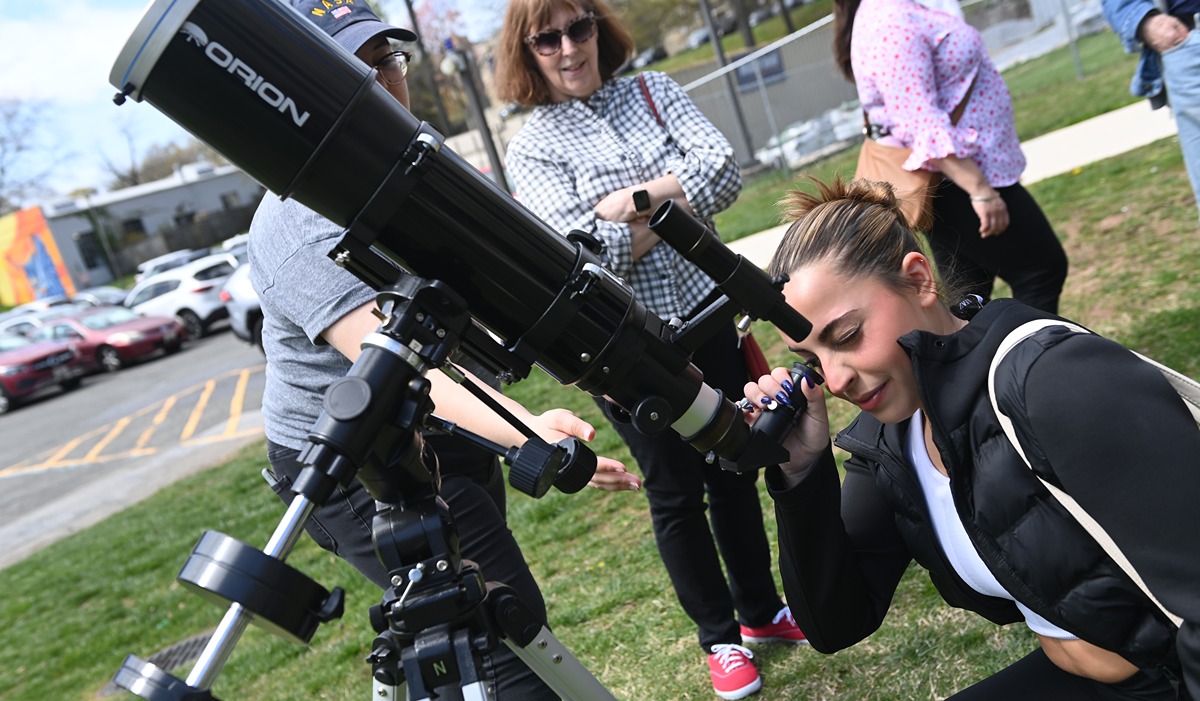 A student is shown how to observe the sun through a solar telescope while Nancy Kilpatrick, University President Peter Kilpatrick’s wife, looks on. (Catholic University/Patrick G. Ryan) 