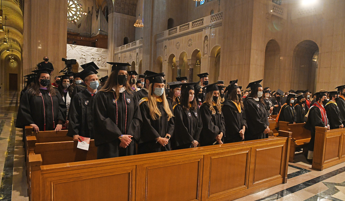 Graduates stand for prayer