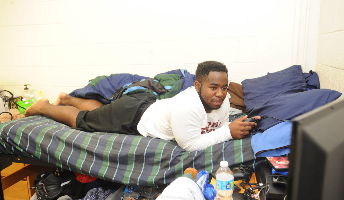 Student lies on bed in residence hall