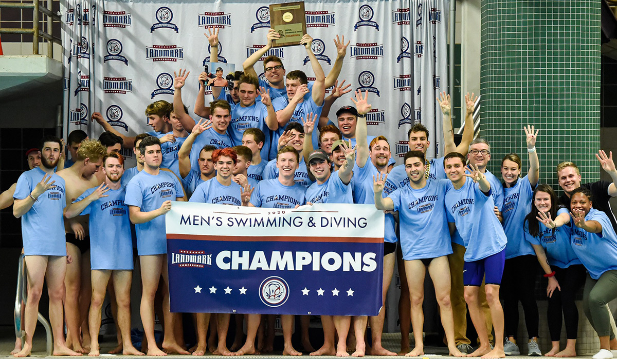 Men's swimming team posing with championship banner