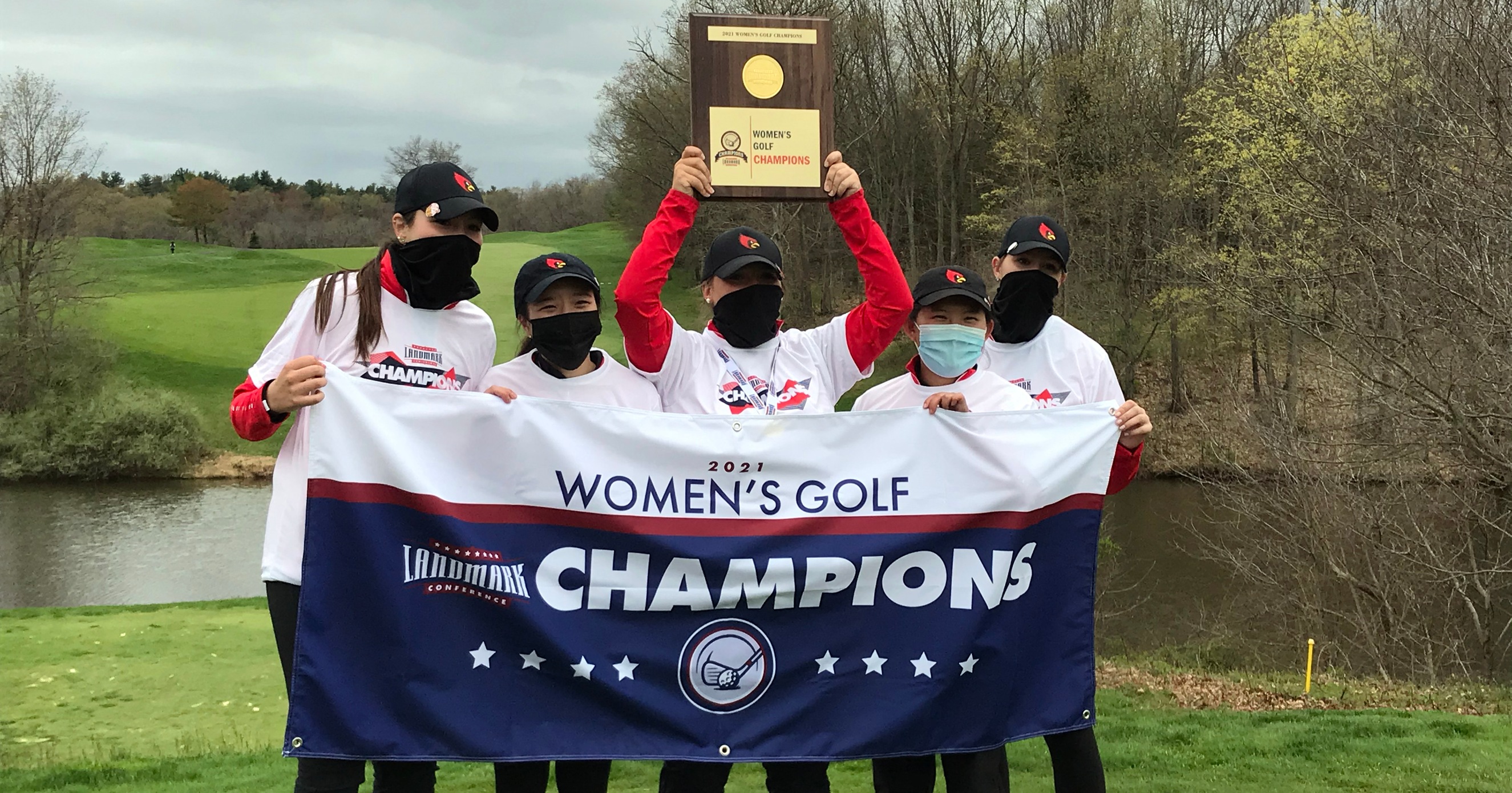 Women's golf team poses with championship banner