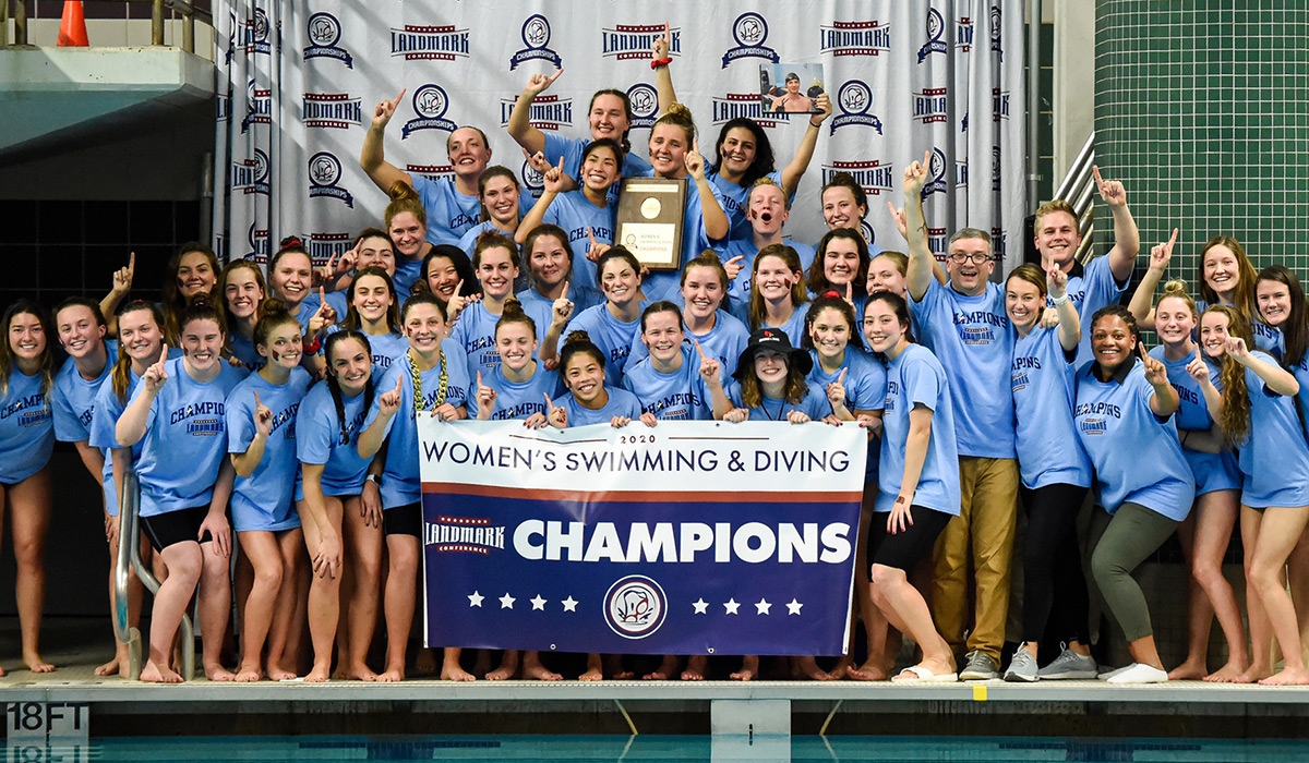 Women's swimming team poses with championship banner