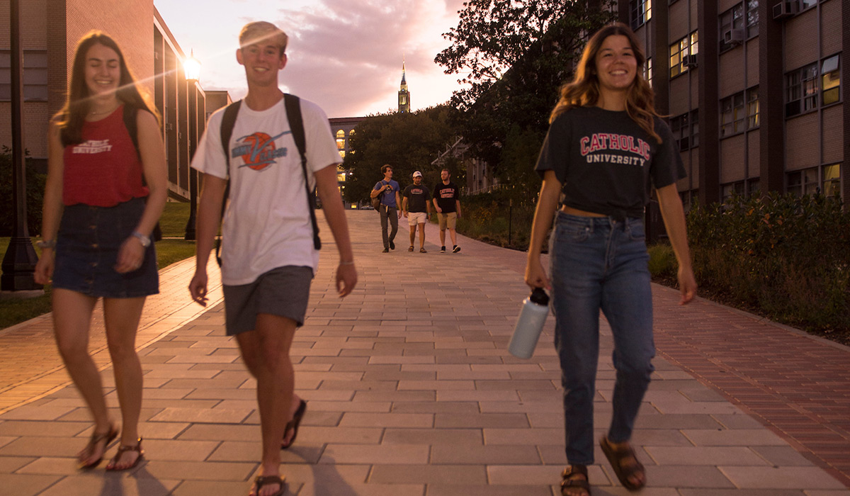 Students walking on brick path at sunset