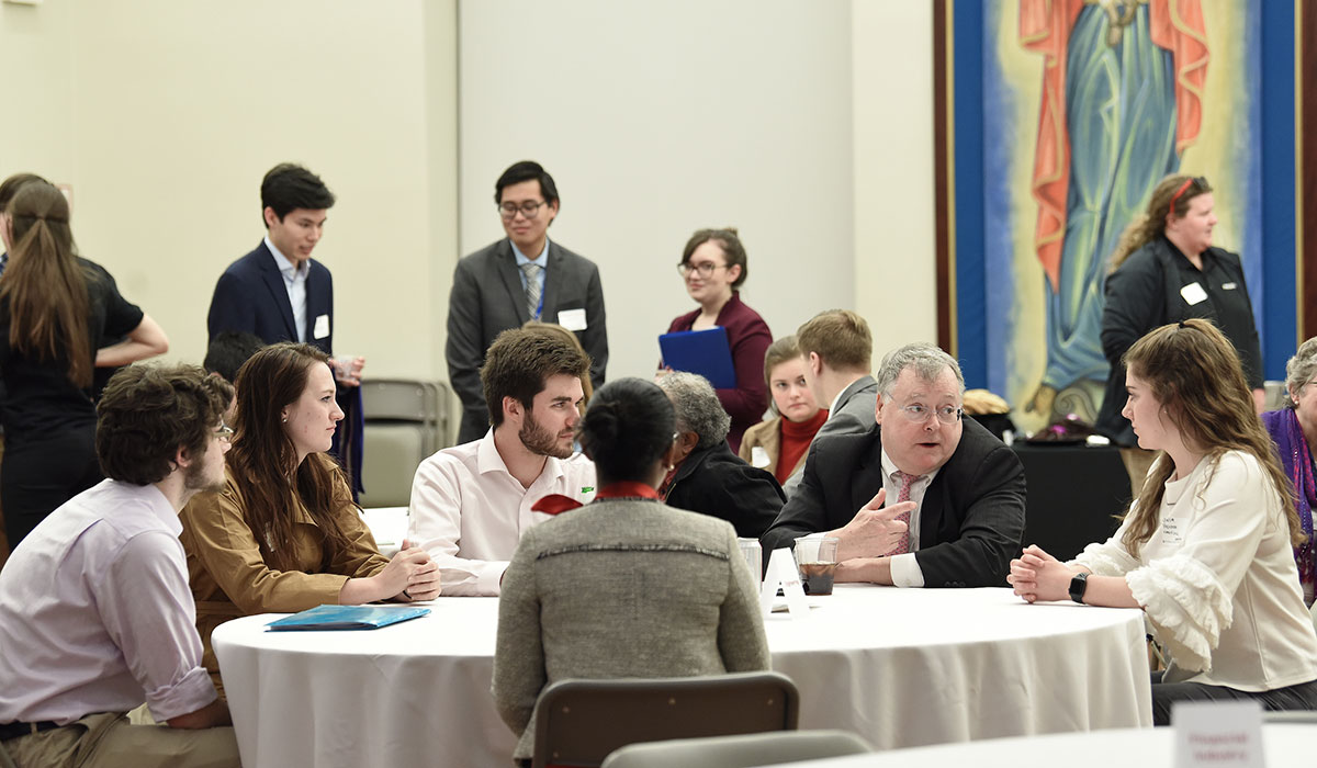Students and alumni at a table talking