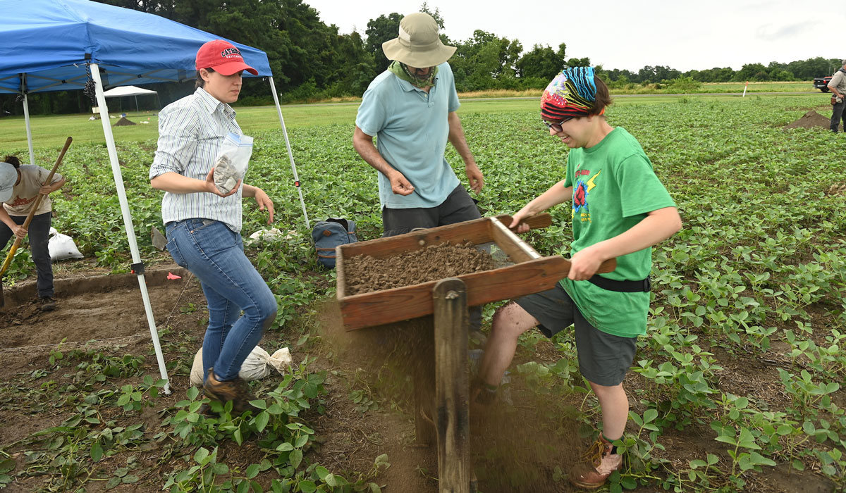 faculty and student sift dirt on archaeological site