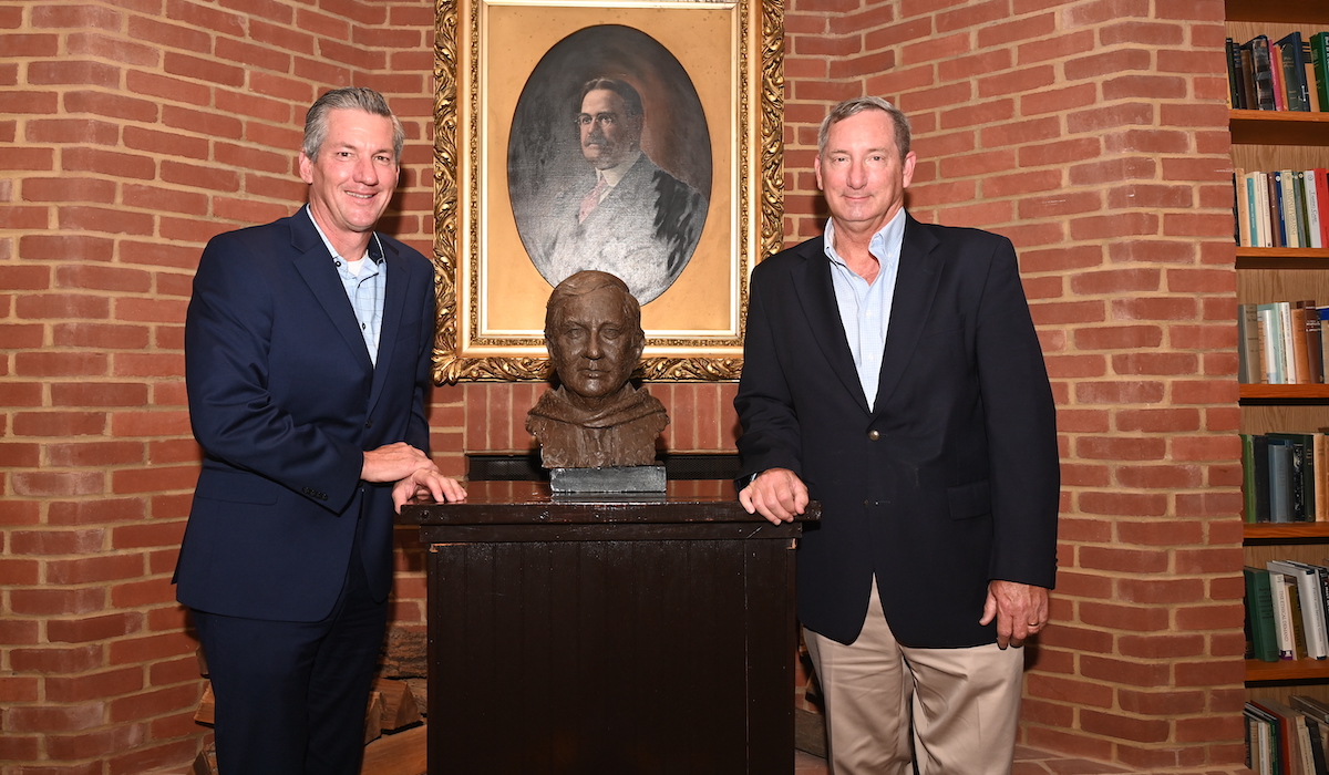 two of Jude Dougherty's sons stand by the bronze bust of Jude Dougherty installed at the School of Philosophy