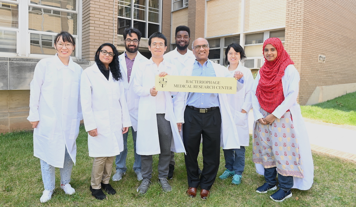 Dr. Rao with his team of researchers holds up a plaque that says Bacteriophage Medical Research Center