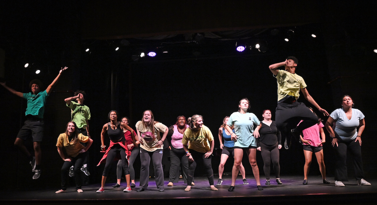 students dancing in colorful shirts during the final dress rehearsal of the summer high school drama institute